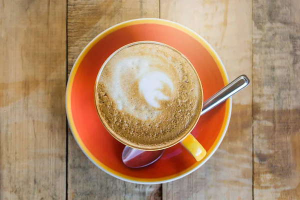 Taza de café naranja latte arte con patrón de hoja sobre fondo de madera, primer plano de café arte por la mañana — Foto de Stock