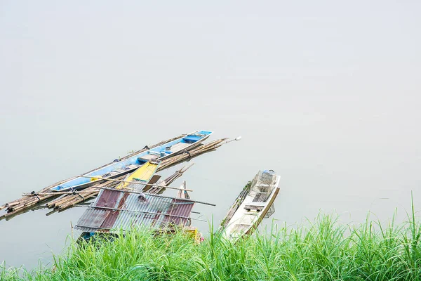 Старая лодка и старый плот пришвартованы на реке — стоковое фото