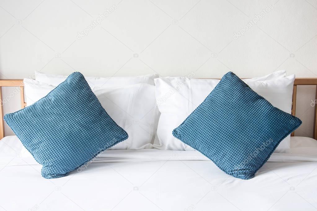 white pillow and blue pillow on bed and with blanket in bedroom