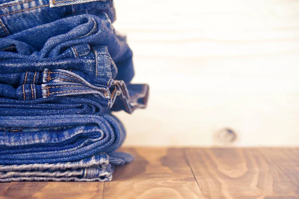 Pilha de jeans em piso de madeira velha, conceito de moda — Fotografia de Stock