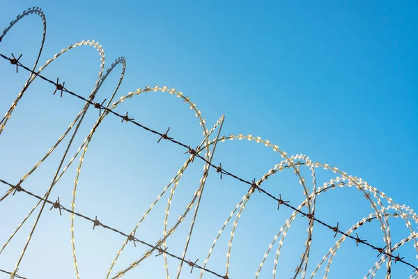 Barbed Wire Fence Used For Protection Purposes Of Property And Imprisonment, No Freedom, Barbed Wire On fence With Blue Sky To Feel Worrying.