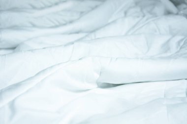 Uzun bir gece uyuduktan sonra yatakta kırışıklıklar bırakan beyaz battaniyenin en üst görüntüsü..
