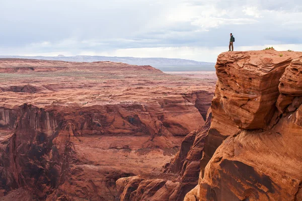 Man staat bovenop een berg. Wandelaar met rugzak staande op een rots, genieten van valleizicht, Arizona — Stockfoto