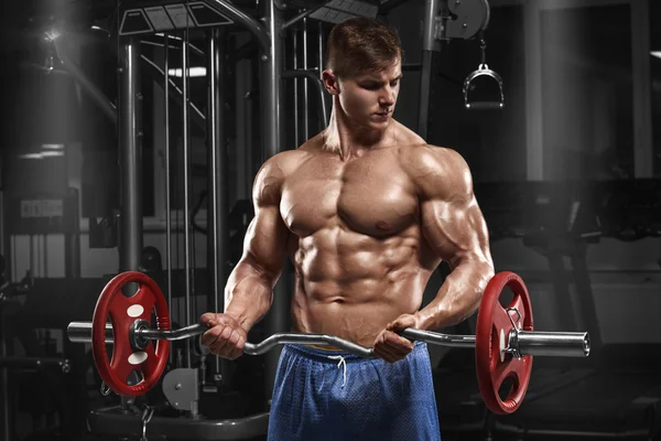 Homem musculoso trabalhando no ginásio fazendo exercícios com barra no bíceps, abdominais fortes tronco nu masculino — Fotografia de Stock