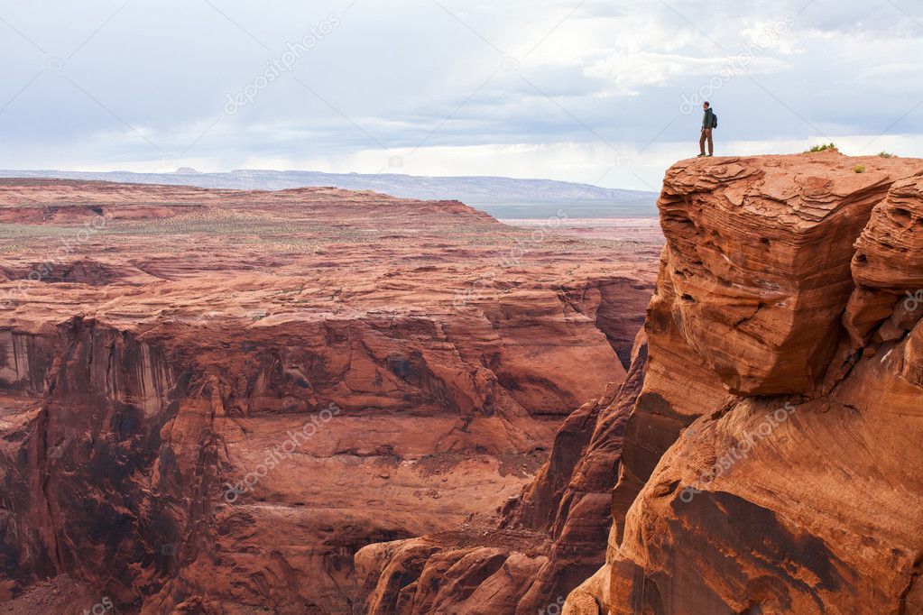 Man stands on top of a mountain. Hiker with backpack standing on a rock, enjoying valley view, Arizona