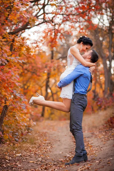 Lachende paar knuffelen in herfst park. Gelukkige bruid en bruidegom in bos, buitenshuis Stockfoto