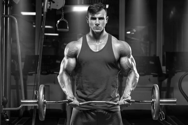 Muscular man working out in gym doing exercises with barbell at biceps — Stock Photo, Image