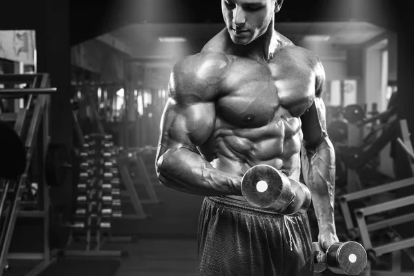 Homem musculoso exercitando-se no ginásio fazendo exercícios com halteres no bíceps, abdominais fortes do tronco masculino — Fotografia de Stock