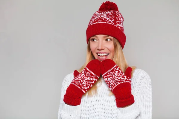 Έκπληκτος ευτυχής όμορφη γυναίκα κοιτάζοντας λοξά σε ενθουσιασμό. Χριστούγεννα κορίτσι φορώντας ζεστό πλεκτό καπέλο και γάντια, απομονώνονται σε γκρίζο φόντο — Φωτογραφία Αρχείου