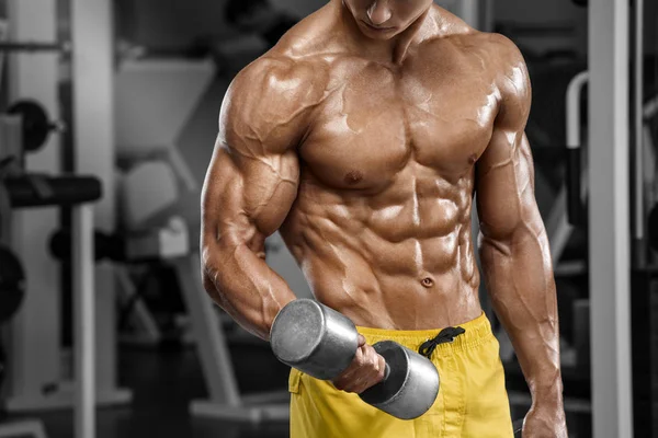 Spor salonunda egzersiz yapan kaslı bir adam. Güçlü erkek, çıplak karın kasları.