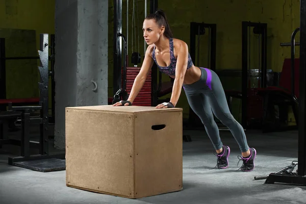 Fitness kvinna gör armhävningar på crossfit box i gymmet. Atletisk flicka träning — Stockfoto