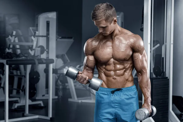 Homem muscular trabalhando fora no ginásio fazendo exercícios com halteres, fisiculturista masculino nu torso abs — Fotografia de Stock