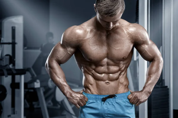 Hombre musculoso en el gimnasio, seis abdominales. Torso nacked macho fuerte, haciendo ejercicio —  Fotos de Stock