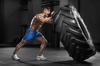 Kaslı adam lastik, güçlü erkek çıplak gövde abs saygısız spor salonunda egzersiz