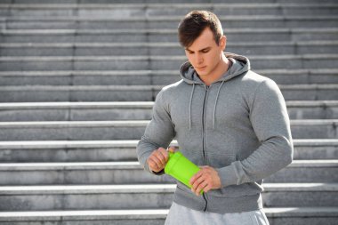 Shaker, açık havada tutan seksi kaslı adam. Genç aktif erkek içme suyu
