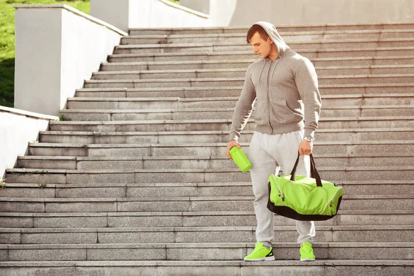 Deporte muscular activo hombre sosteniendo agitador y bolsa de deporte, al aire libre — Foto de Stock