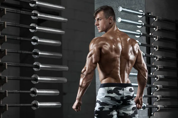 Vista trasera hombre musculoso posando en el gimnasio, mostrando la espalda y tríceps. Torso desnudo macho fuerte, ejercitando —  Fotos de Stock