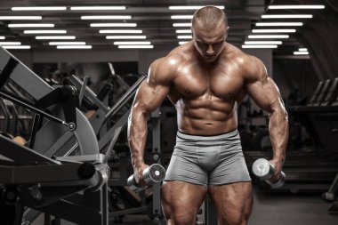 Spor salonunda egzersiz yapan kaslı bir adam. Güçlü erkek, çıplak karın kasları.