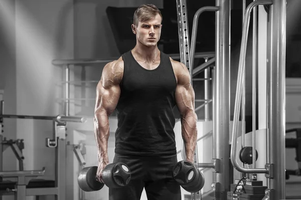 Мускулистый мужчина тренируется в спортзале, делает упражнения, красивый сильный мужчина — стоковое фото