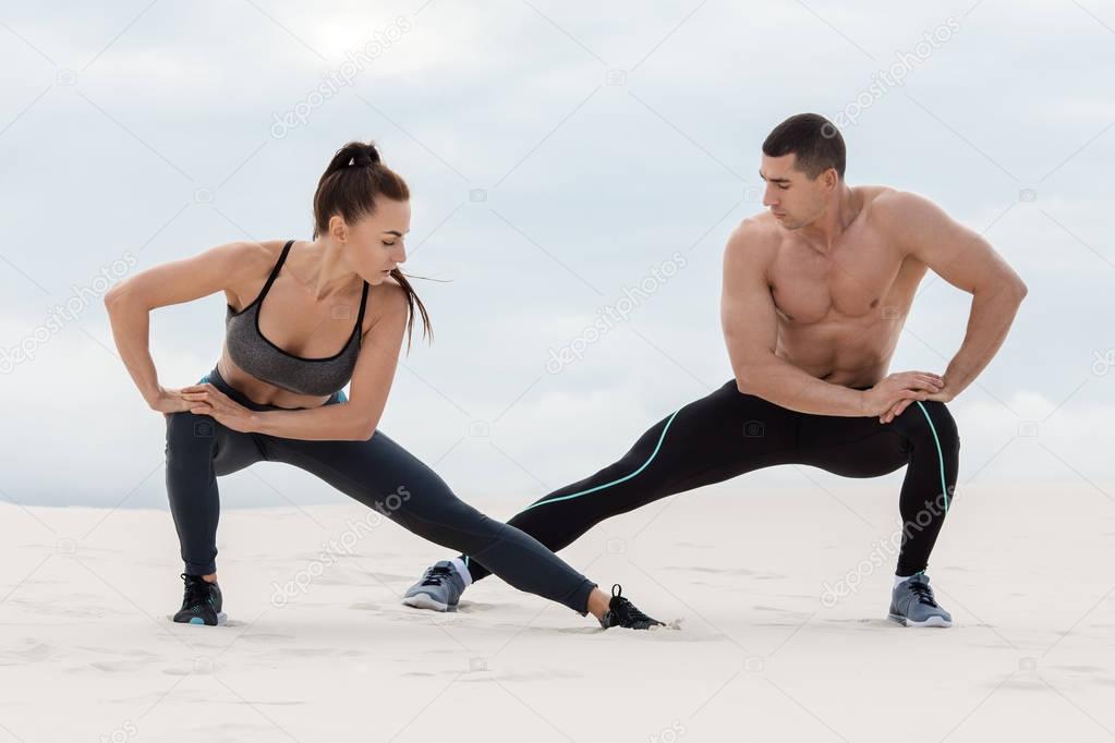 Sporty fitness couple doing stretching exercises outdoors. Beautiful athletic man and woman