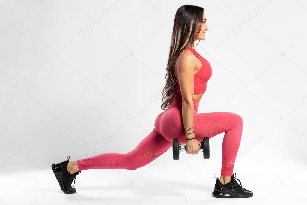 Fitness woman doing lunges exercises for leg muscle workout training. Active girl doing front forward one leg step lunge exercise, on the gray background