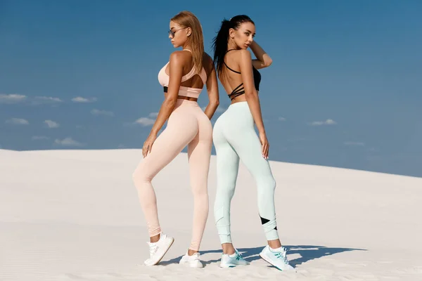 Beautiful fitness models in sportswear. Couple athletic girls in leggings outdoor