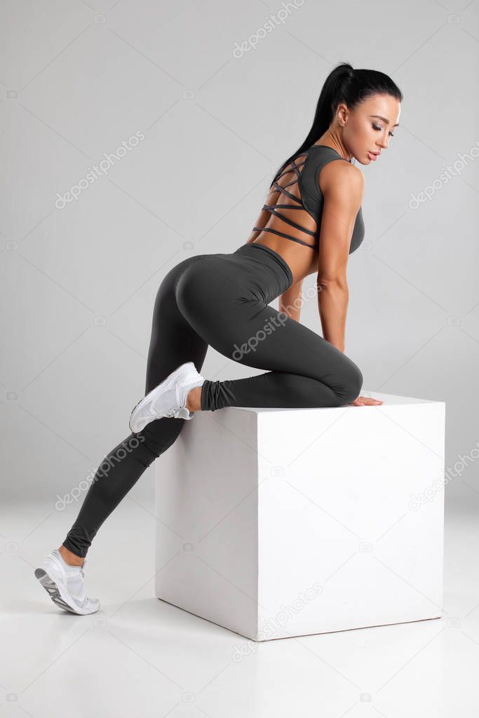 Fitness woman in leggings on gray background. Athletic girl with beautiful butt