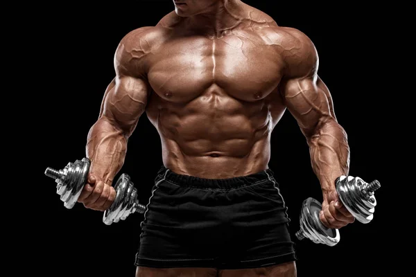 筋肉の男は 黒の背景に隔離されたダンベルで演習をして 働いています 強い男裸の胴体の腹筋 — ストック写真