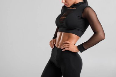 Fitness kadın abs ve düz karın gösteren, gri arka plan üzerinde izole. Güzel atletik kız, şekilli karın