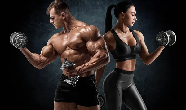 Dambıllarla spor yapan bir çift. Kaslı adam ve kadın kaslarını gösteriyor.