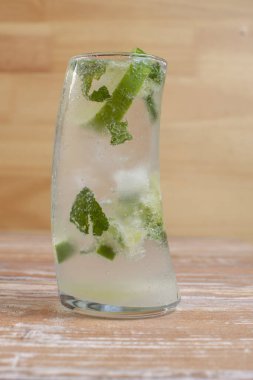 İtalyan aromalı limonlu soda ve naneli yaprak ve ahşap zemin üzerinde bir sürü buz.