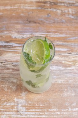 İtalyan aromalı limonlu soda ve naneli yaprak ve ahşap zemin üzerinde bir sürü buz.