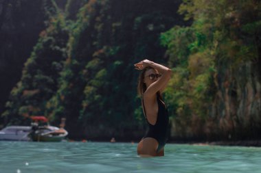 Mavi lagündeki Phi Phi adasında siyah mayo giymiş genç seksi kız.