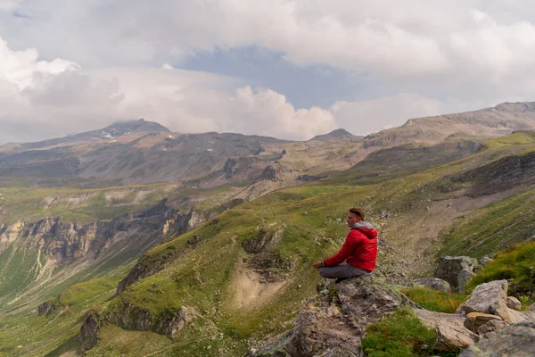 Fiatalember Piros Kabátban Köveken Bámulatos Kilátás Nyílik Alpok Hegyre — Stock Fotó
