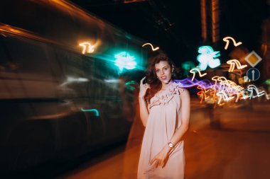 Yazlık elbiseli genç bir kız gece şehirde dolaşıyor.