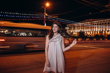 Yazlık elbiseli genç bir kız gece şehirde dolaşıyor.