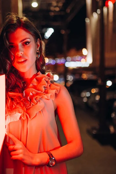 Yazlık elbiseli genç bir kız gece şehirde dolaşıyor.