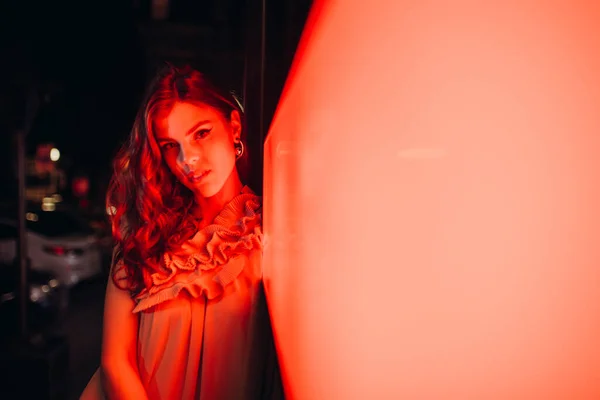 Yazlık elbiseli genç bir kız gece şehirde dolaşıyor.