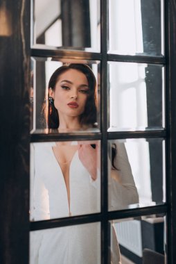 Beyaz parlak gelinlik içinde kahverengi saçlı güzel bir gelin fotoğraf stüdyosunda poz veriyor.