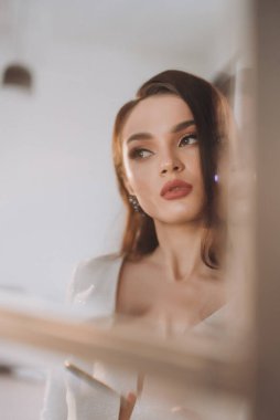 Beyaz parlak gelinlik içinde kahverengi saçlı güzel bir gelin fotoğraf stüdyosunda poz veriyor.