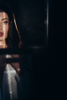 Beyaz parlak gelinlik içinde kahverengi saçlı güzel bir gelin fotoğraf stüdyosunda poz veriyor.