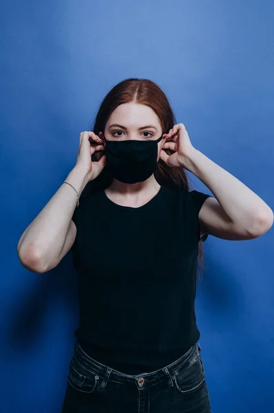 Mavi arka planda antiviral maskeli güzel bir kız.
