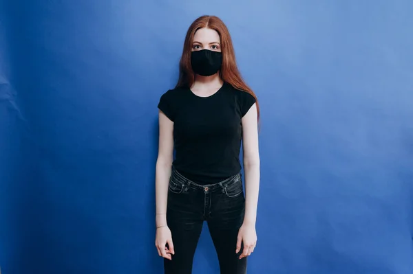 Mavi arka planda antiviral maskeli güzel bir kız.