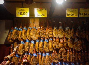 Jamon, İspanyol jambonu dükkanda satılıyor. Ayaklar fiyat etiketleriyle tezgahta asılı. Calella, İspanya. Görünüm.