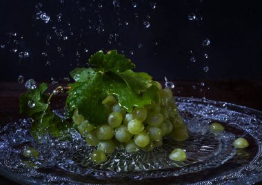 Koyu bir arka planda yeşil üzümler ve sprey