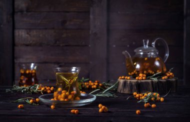 Ahşap arka planda cam çaydanlıkta deniz dikenli çay.