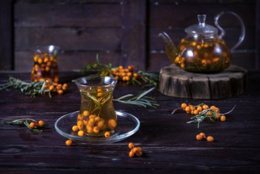 Ahşap arka planda cam çaydanlıkta deniz dikenli çay.