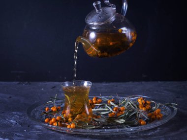 Ahşap arka planda cam çaydanlıkta deniz dikenli çay.