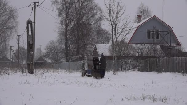 Muž v zimě otáčí bránou studny, aby zvedl vědro s vodou. čerpá vodu — Stock video