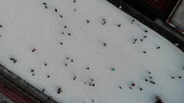 Mensen schaatsen overdag op een verlichte ijsbaan. Bovenaanzicht vanuit de lucht. — Stockvideo